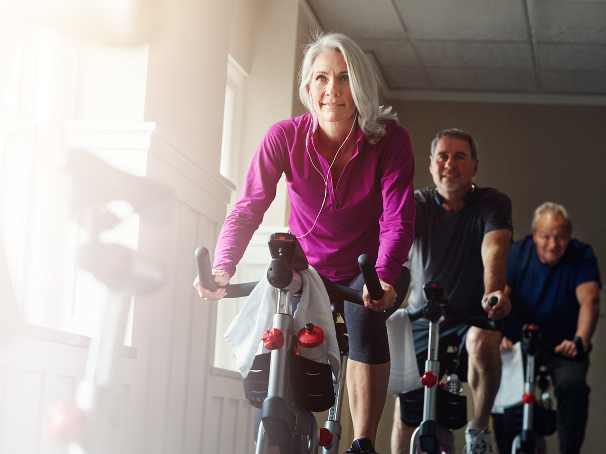 Older woman leading a spin class on an exercise bike, tracking her fitness progress