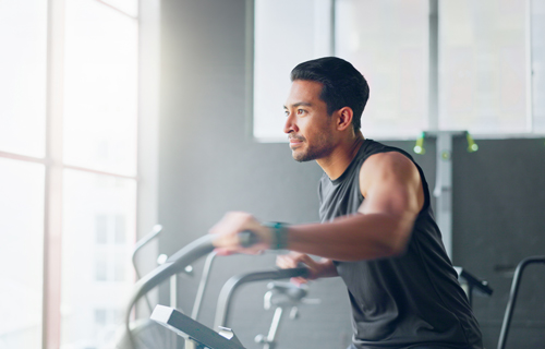Man using a treadmill at the gym while tracking his fitness progress