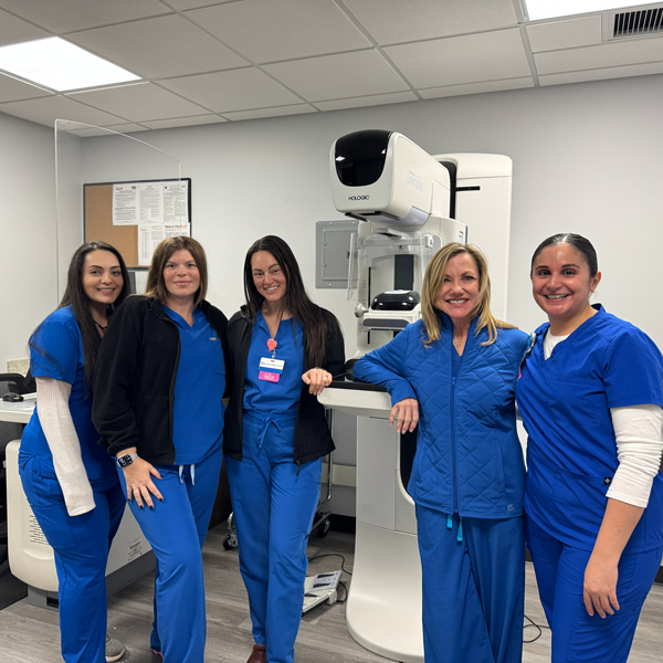 RIA Jupiter technologists standing beside the 3D mammography unit used for Enhanced Breast Cancer Detection