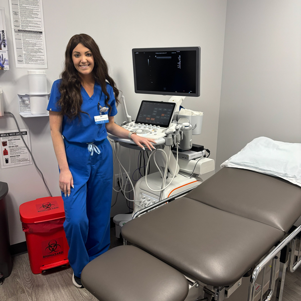Ultrasound technologist standing beside the ultrasound machine in an RIA Jupiter exam room